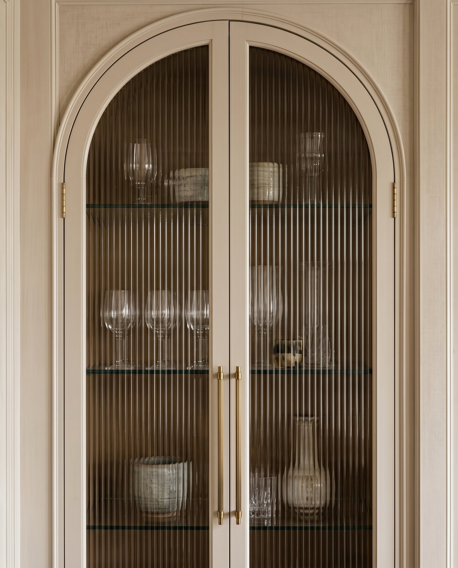 Custom built-in cabinetry with arched glass and brass detail
